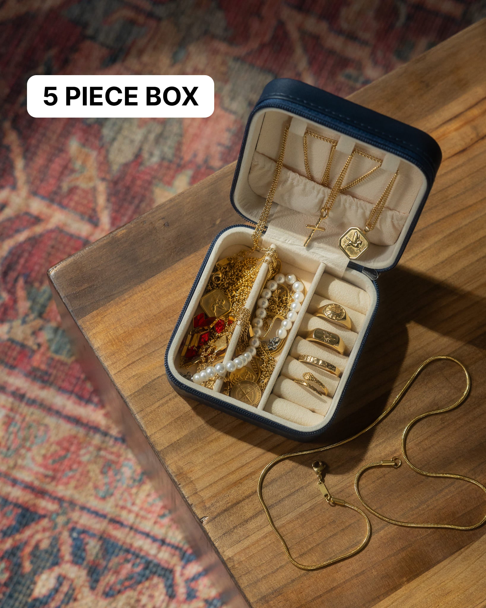 Hands hold a travel jewelry box open to show gold chains and rings inside