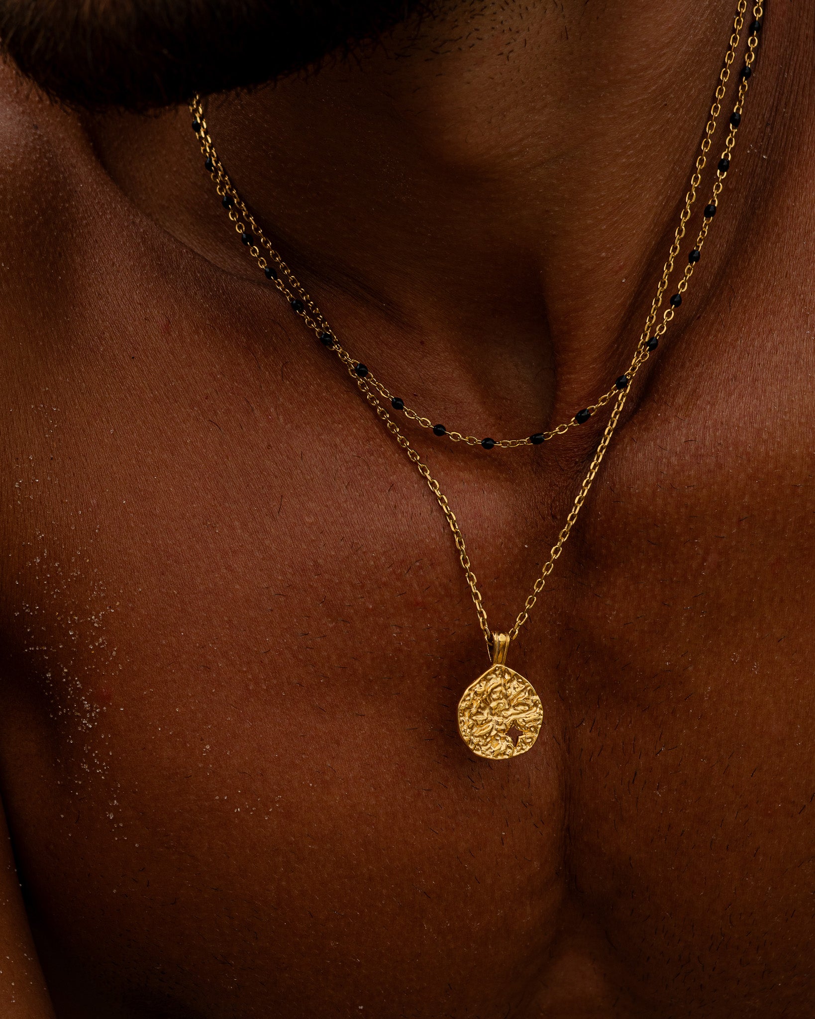 Gold chain necklace with black beads worn around the neck