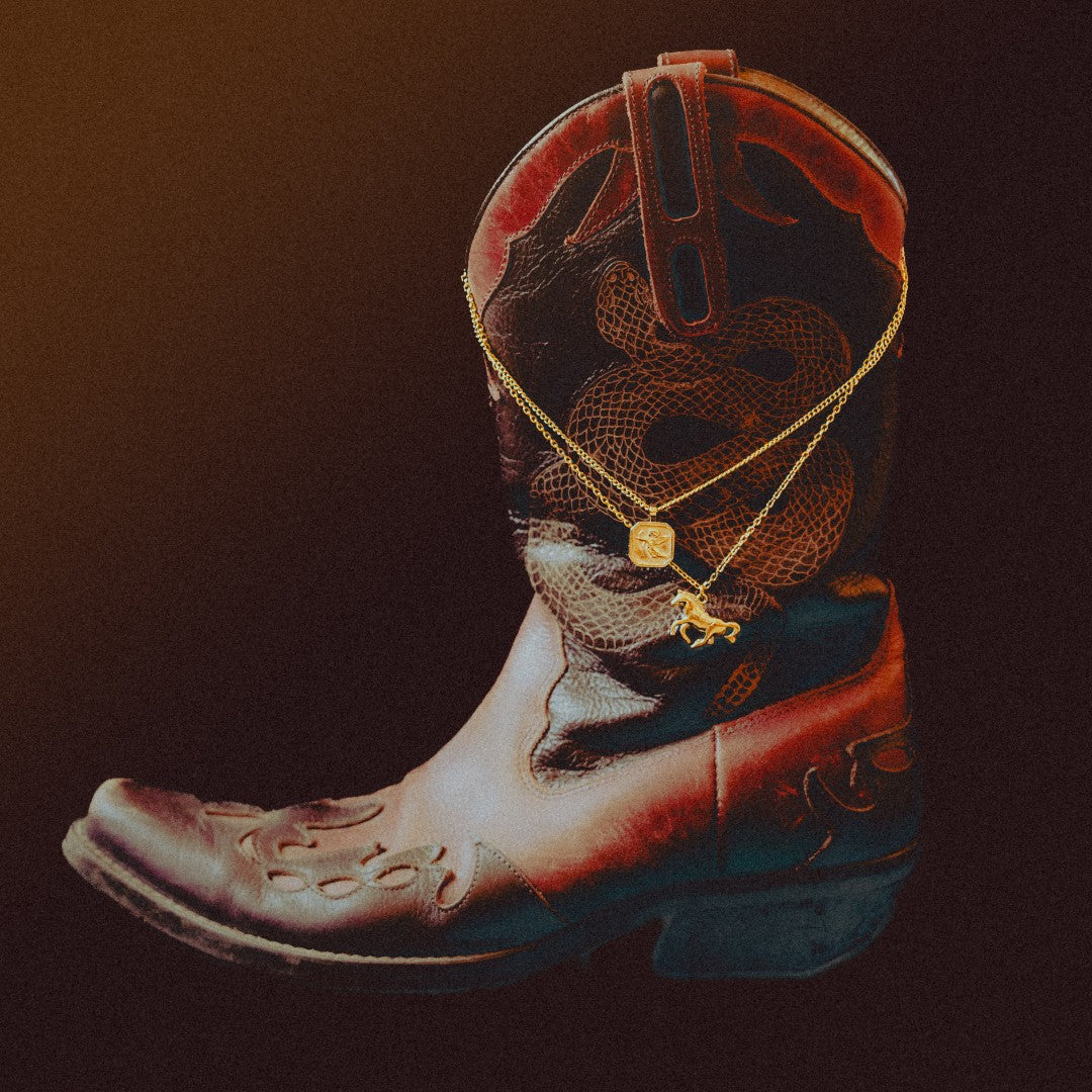 Gold necklaces draped over a brown cowboy boot in a bold jewelry display