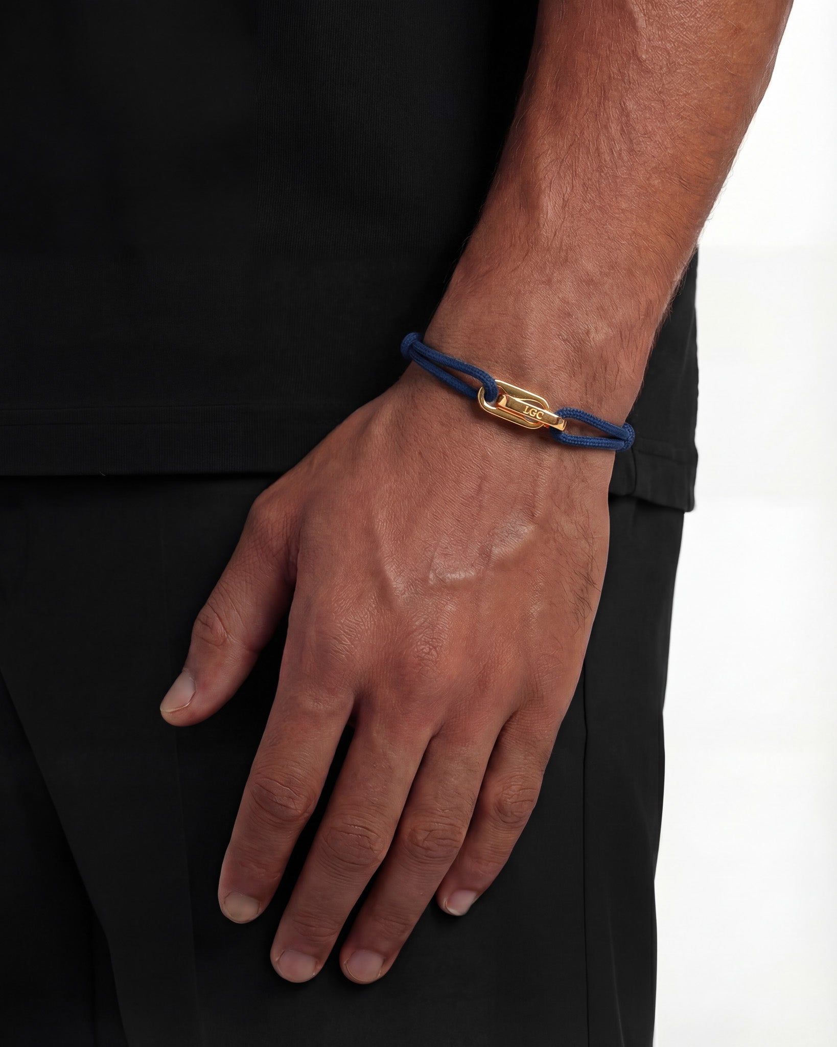 Wrist wearing Atlantis Gold Bracelet in blue cord with gold clasp