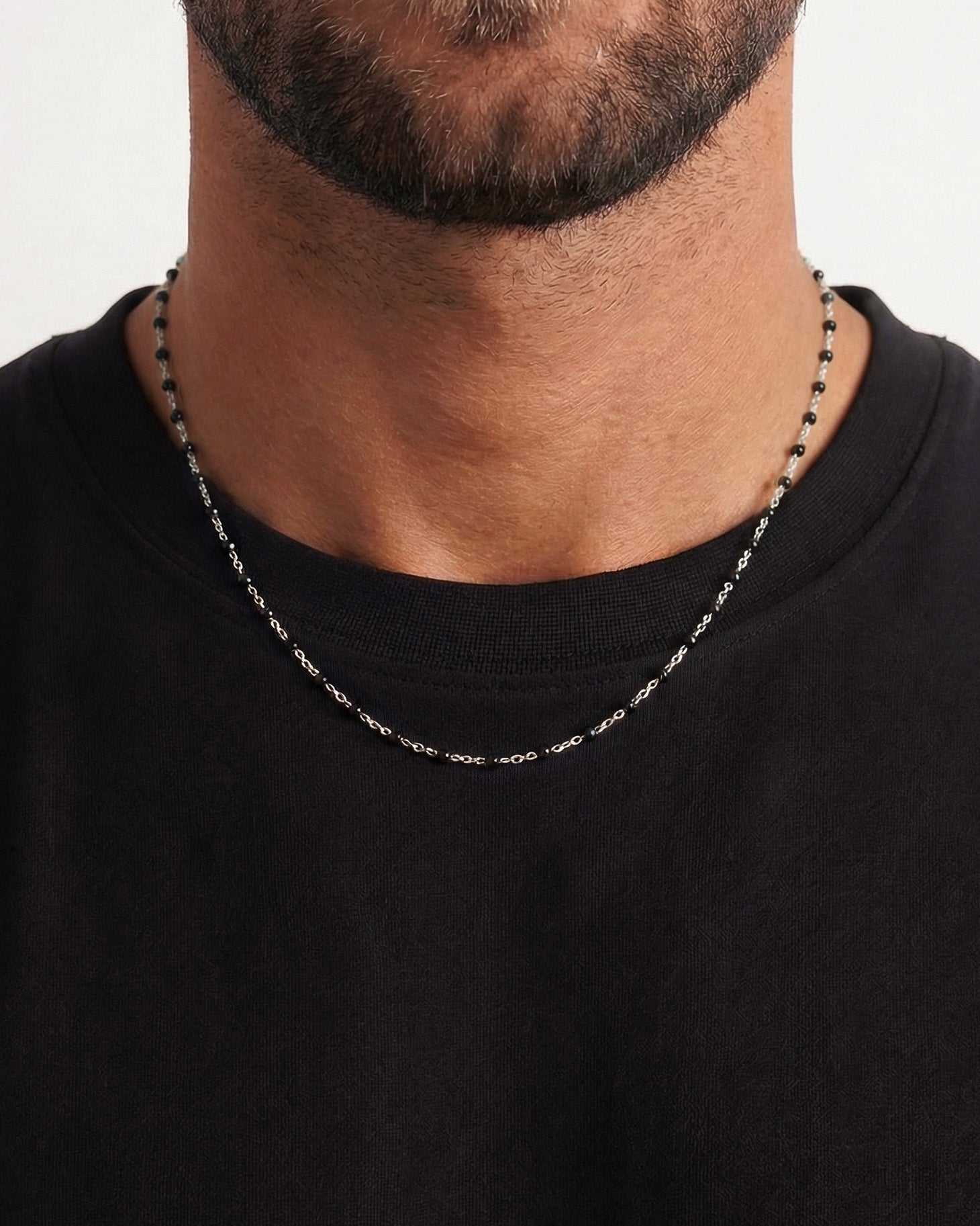 GEM silver chain necklace with small black beads worn on a man’s neck over a black shirt