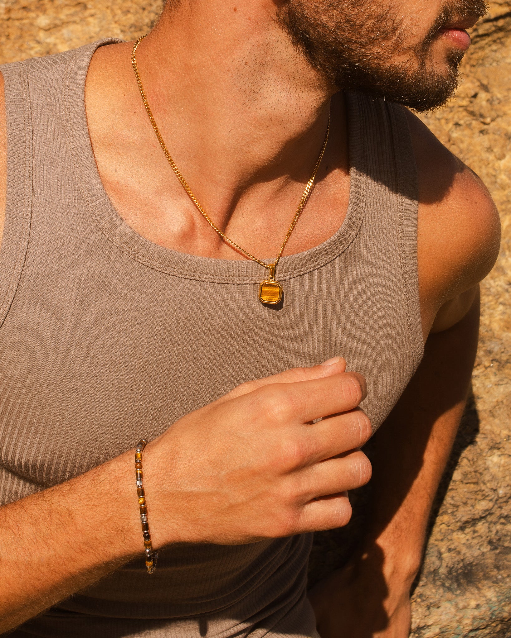 Frontal view of the NOVA GOLD NECKLACE with a square amber pendant resting on a man's chest.