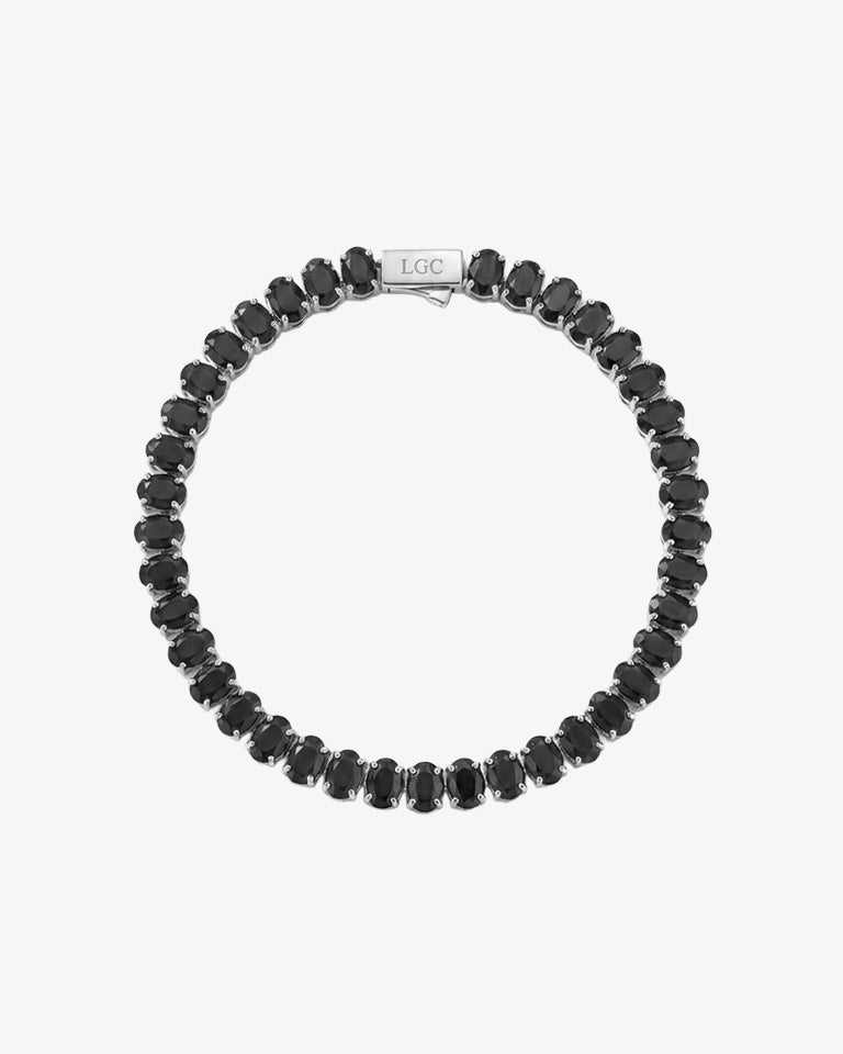Oval black diamond tennis bracelet laid flat on a white background